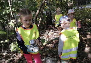 Grupa dzieci na leśnej polanie zbierają śmieci